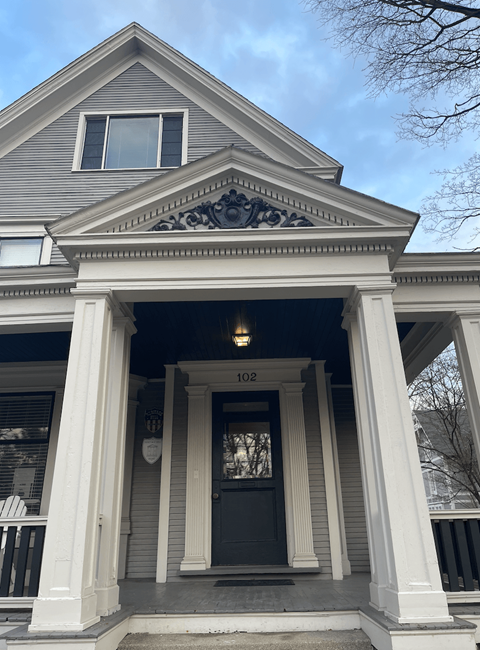 the front of the house has a large porch with columns and a window above the door